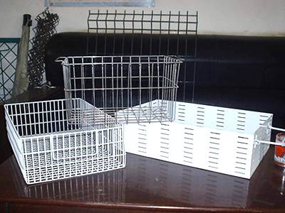 Three galvanized wire baskets on a red table, and some wire panels beside table.